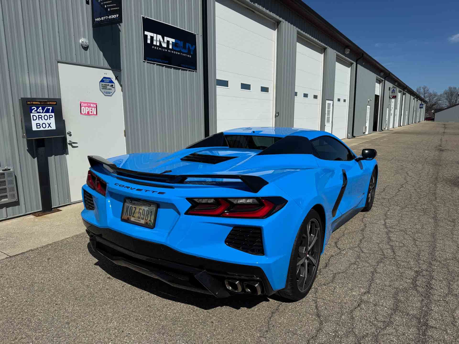 A blue sports car is parked in front of a building.
