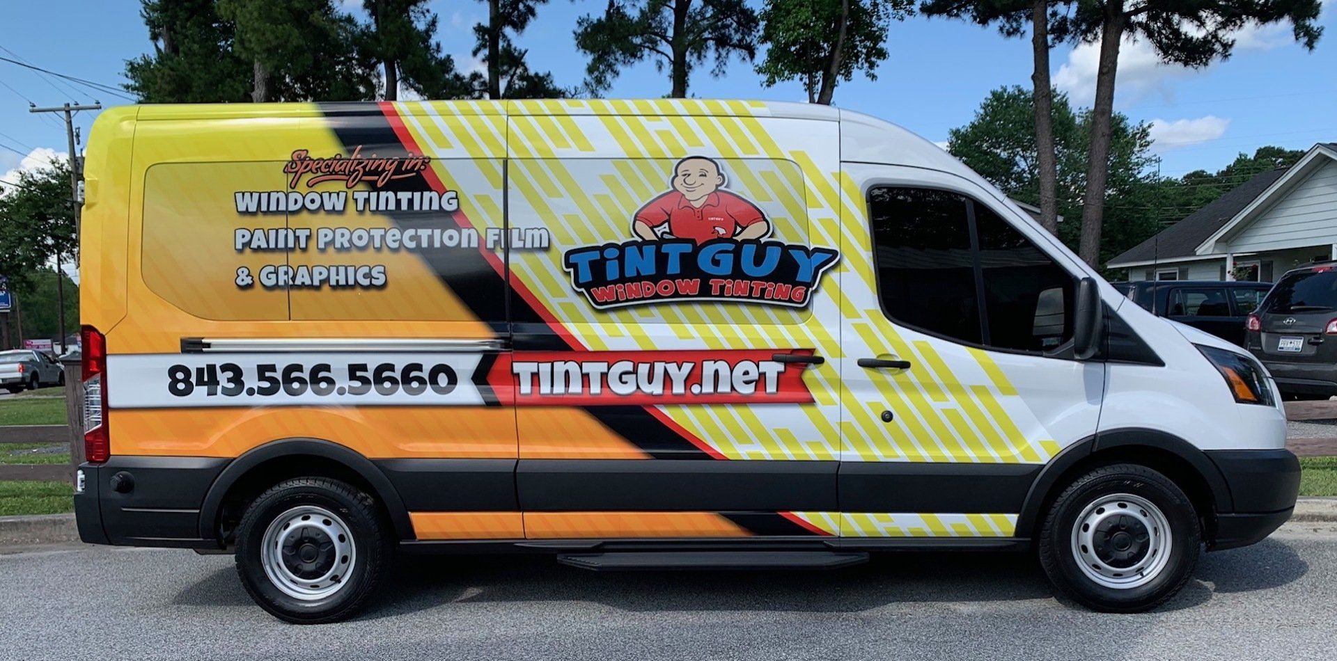 A yellow and white van is parked on the side of the road.