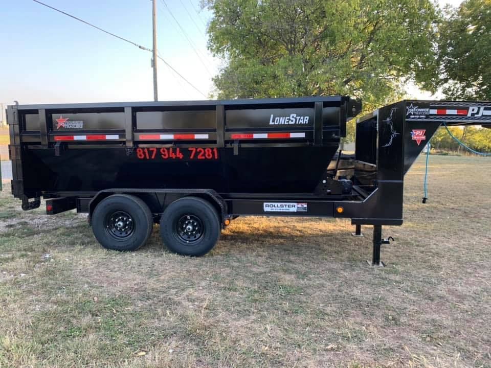 A dump trailer is parked in a grassy field.
