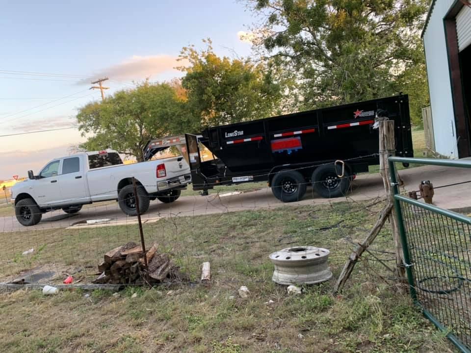 A white truck is towing a dumpster on a trailer.