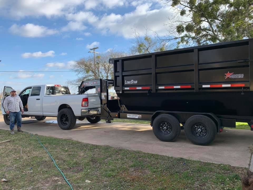 A white truck is parked next to a black dumpster trailer.