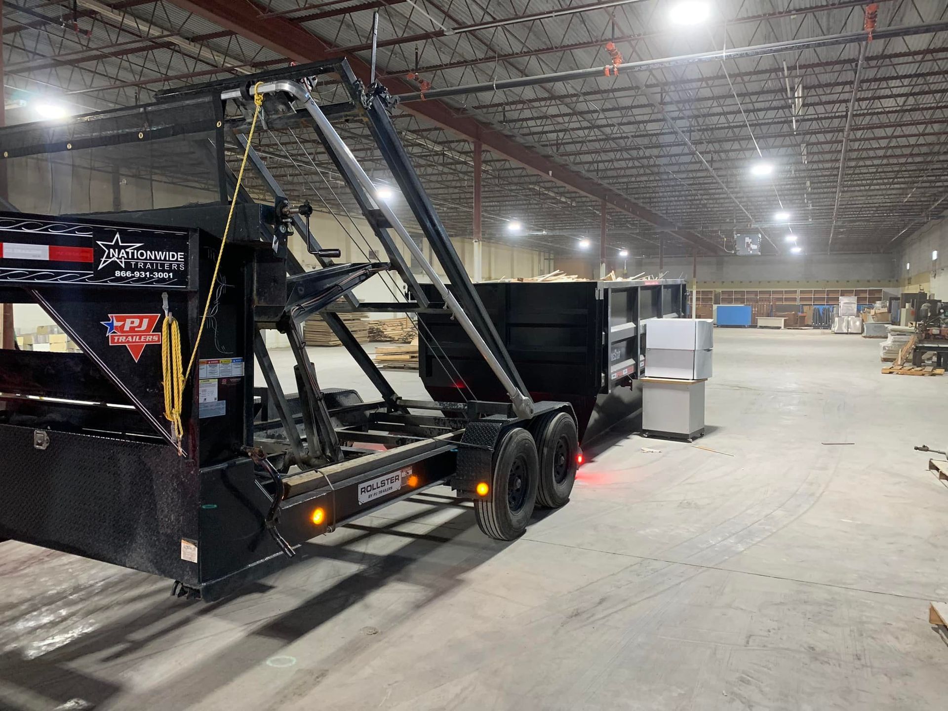 A dumpster trailer is parked in a large warehouse.