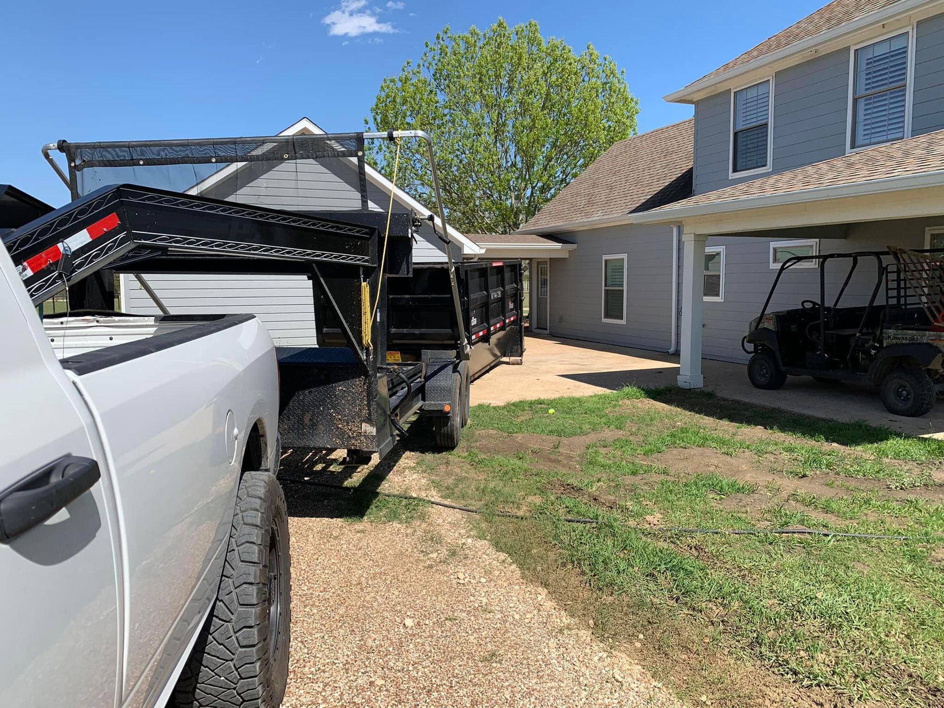 A truck with a trailer attached to it is parked in front of a house.