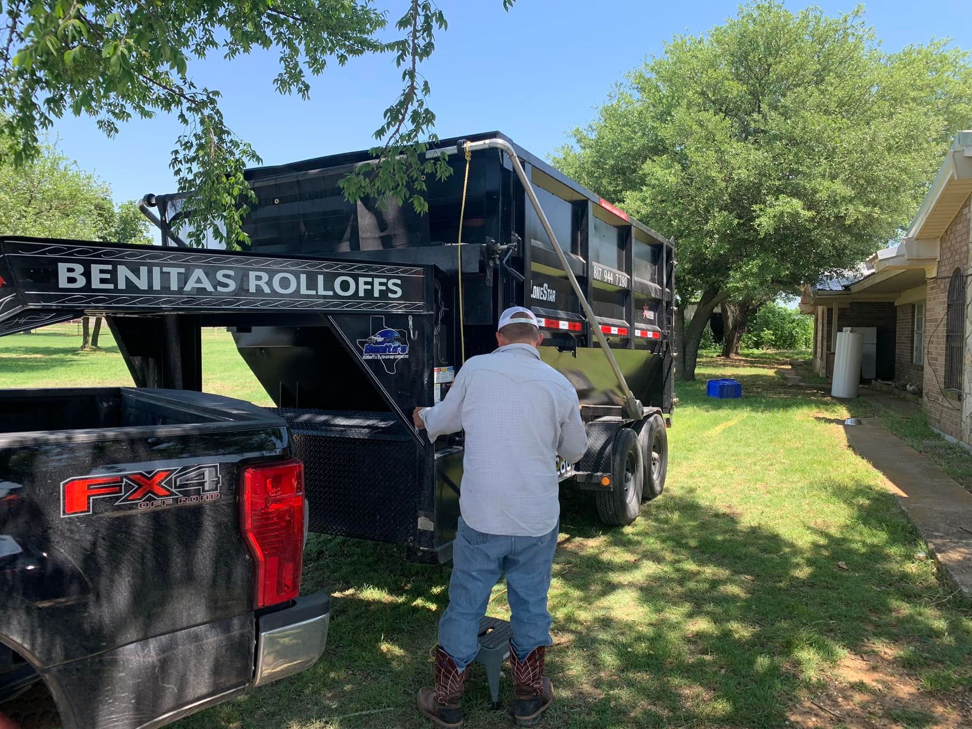 A man is standing in front of a black dump truck.