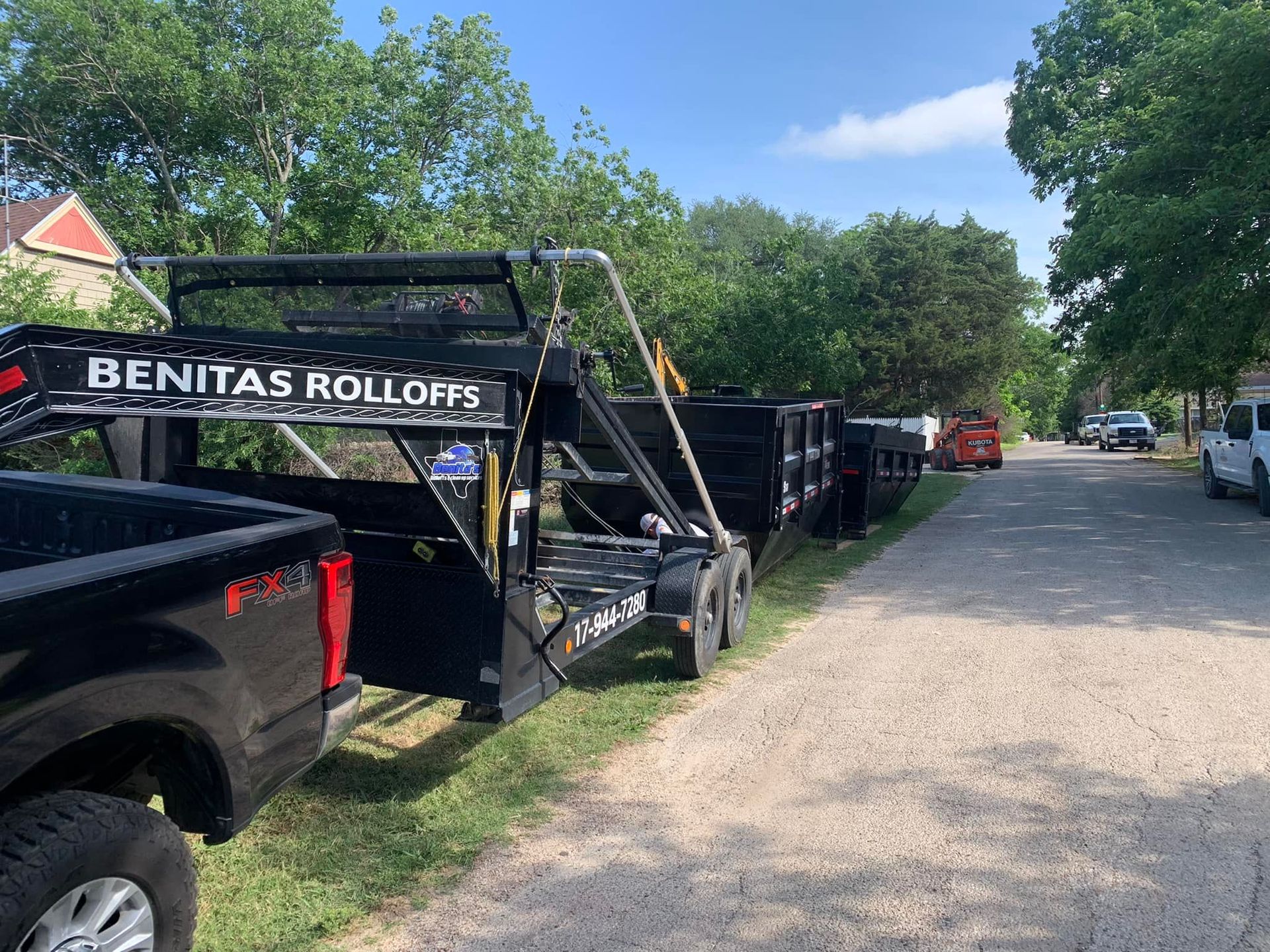 A black truck is parked on the side of the road next to a trailer.