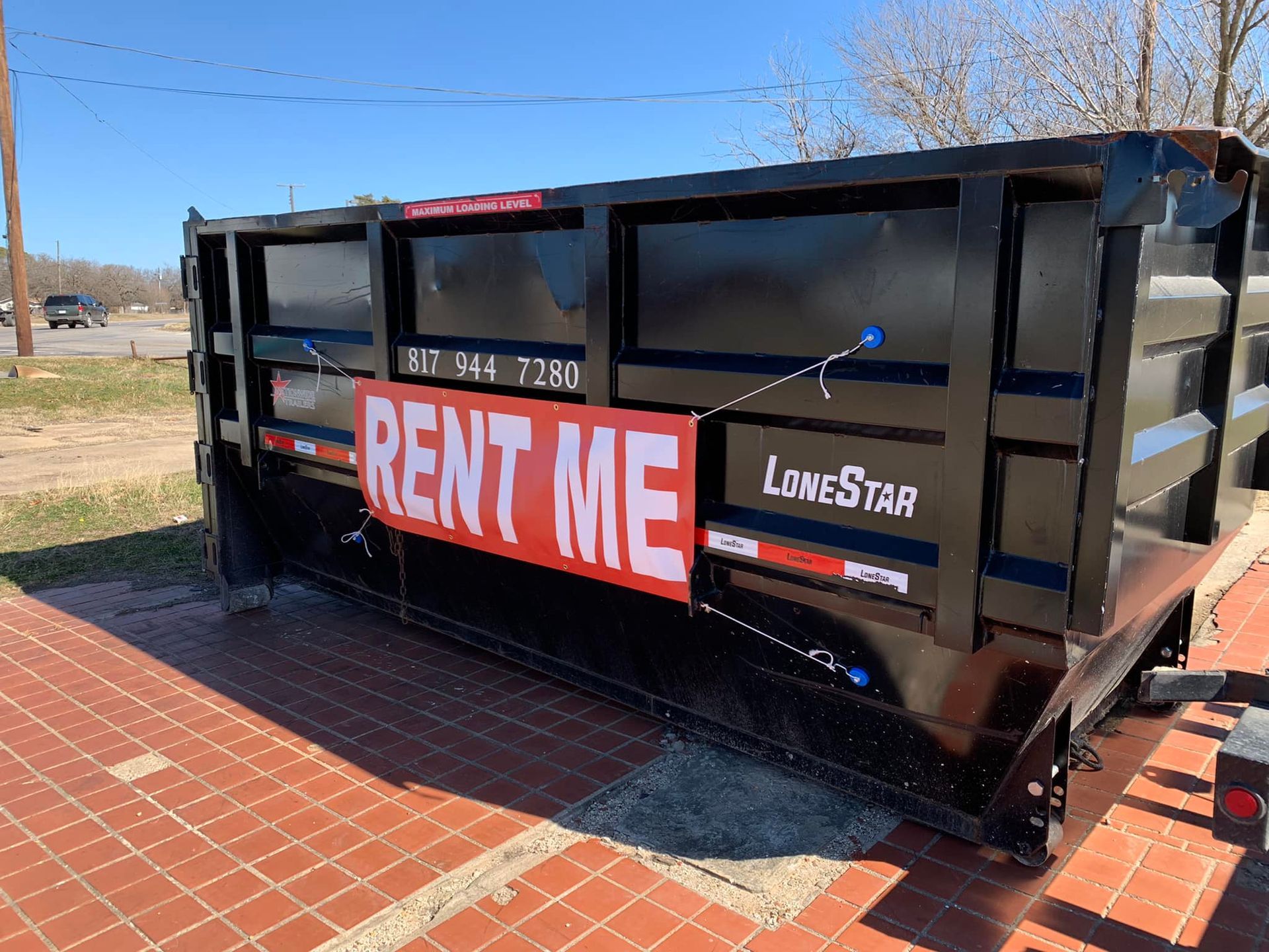 A dumpster with a sign that says `` rent me '' is parked on a sidewalk.