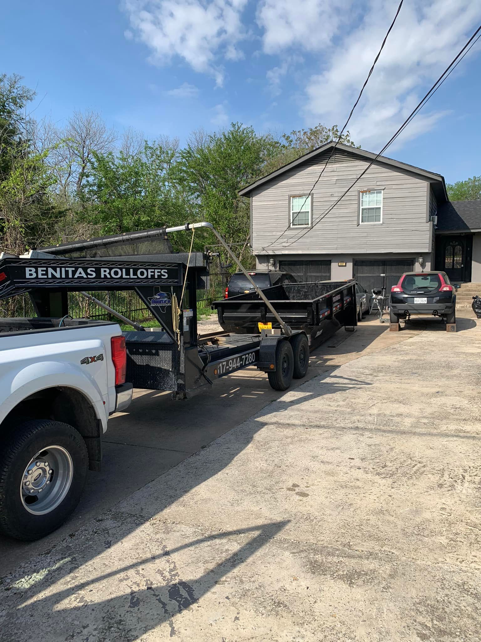 A truck is towing a trailer in front of a house.