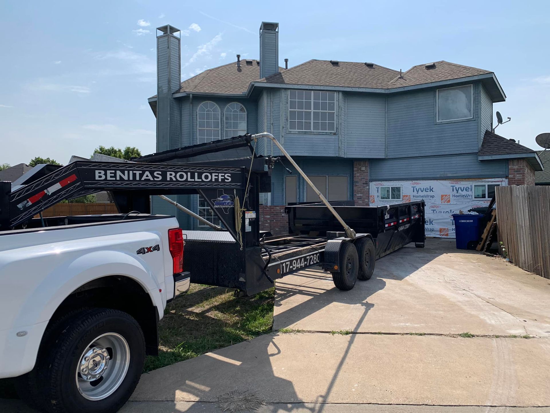 A truck with a trailer attached to it is parked in front of a house.