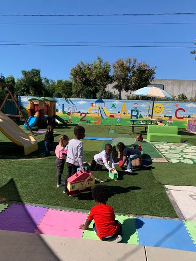 Children playing on a colorful playground with a painted mural and a slide.