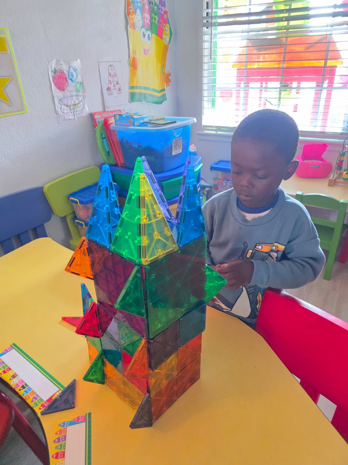 Boy building with colorful magnetic tiles at a table.