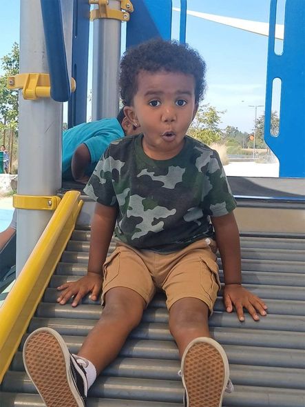Boy sitting on a playground slide, making a face.