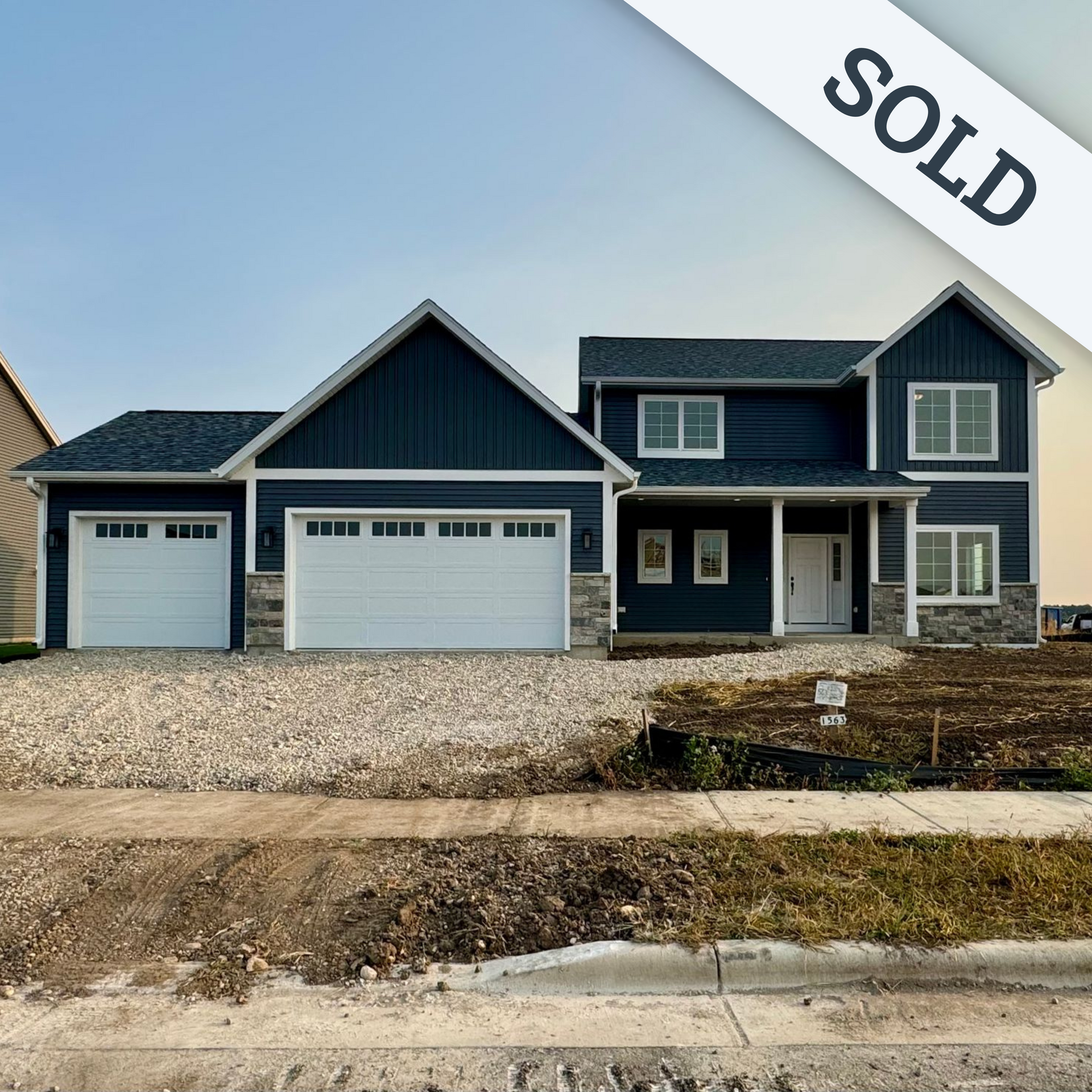 A large house with two garage doors is sitting on top of a dirt hill.