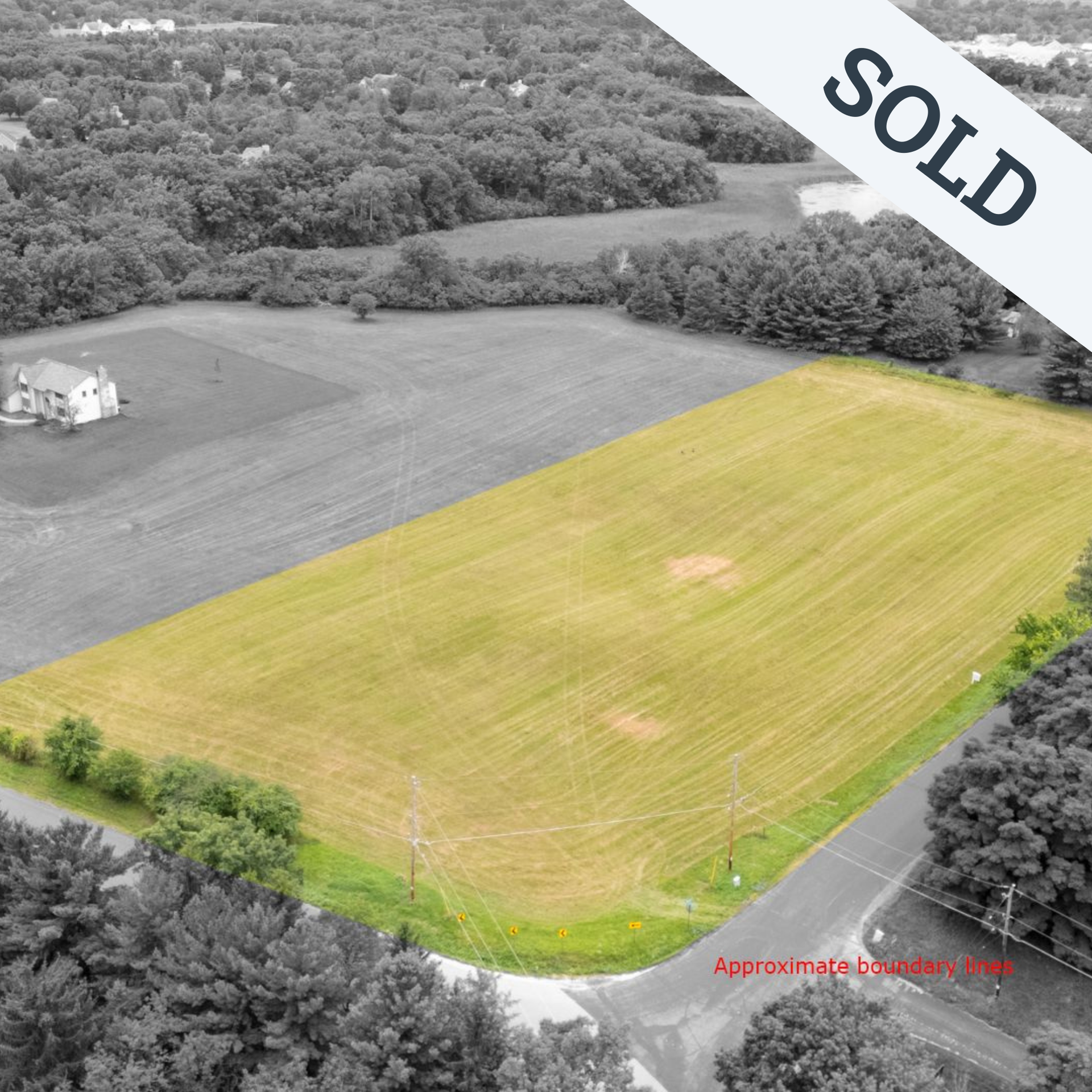 An aerial view of a large grassy field surrounded by trees