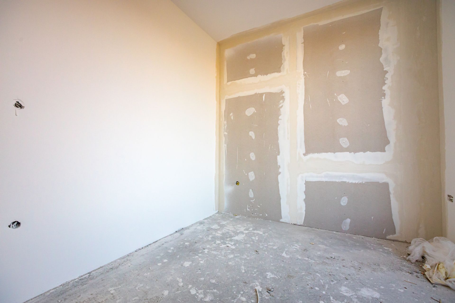 Interior room under construction, with drywall partially installed on the walls and a concrete floor.