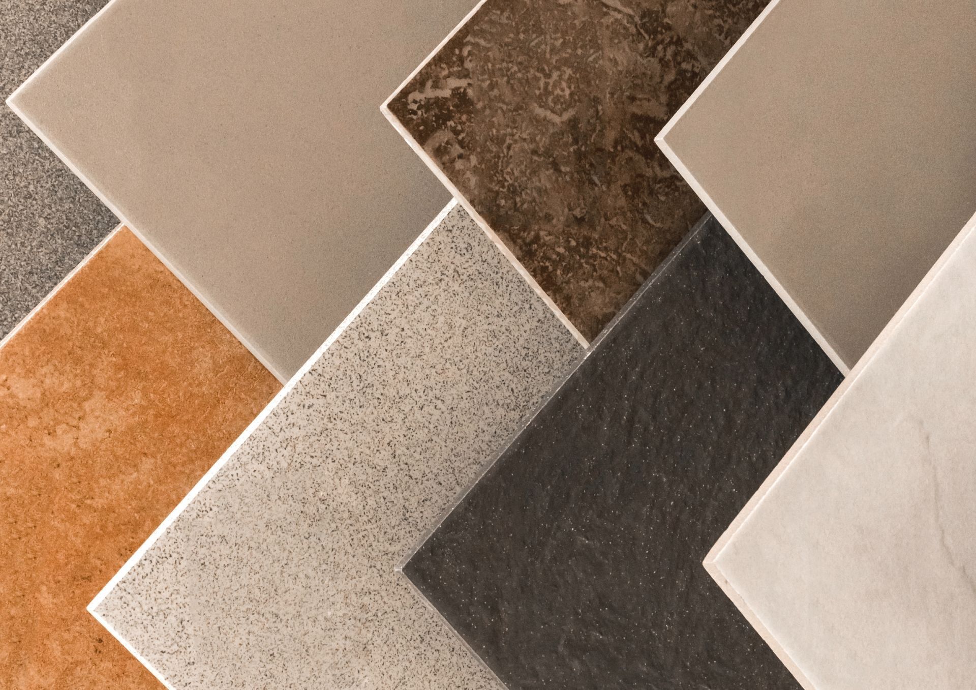 Assortment of various ceramic tiles in shades of brown, gray, and beige, arranged in a diagonal pattern.