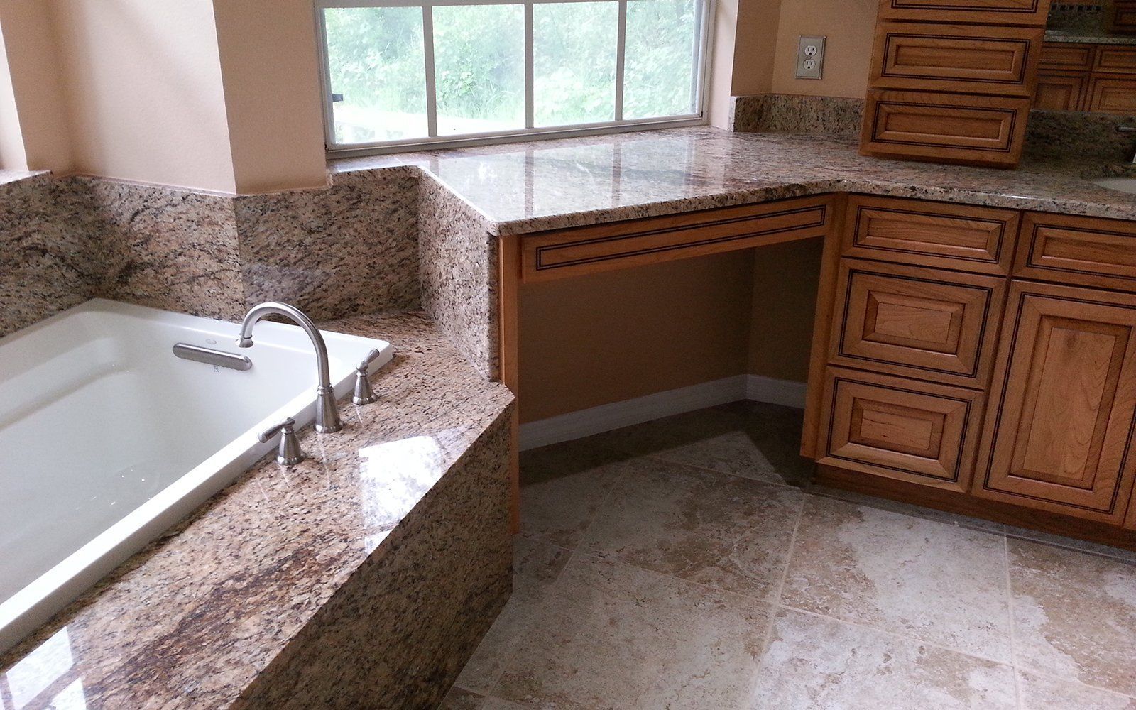 Bathroom with a bathtub, granite countertop, wooden cabinets, and a window.