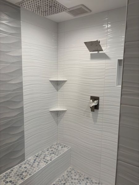 White tiled shower with built-in bench and shelves, two showerheads, and a faucet.
