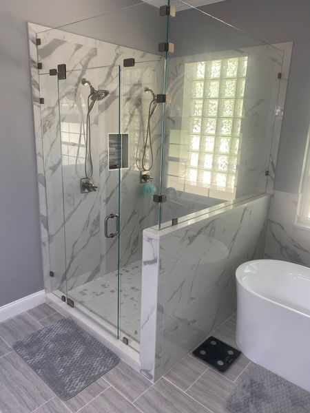 Modern bathroom with marble tile shower, glass door, and free-standing tub.