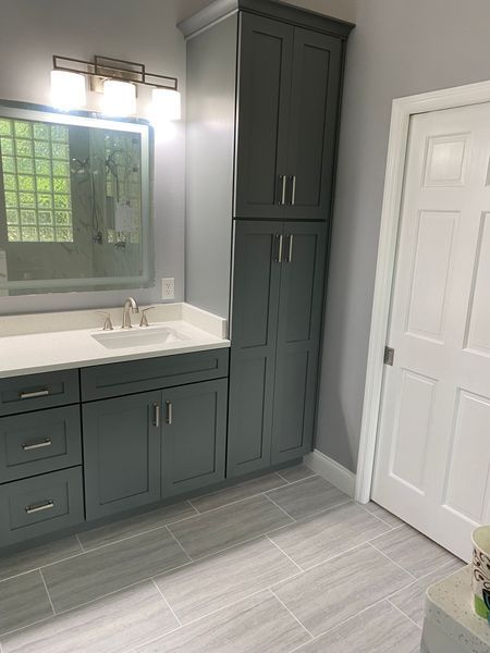Gray and white bathroom with cabinetry, sink, and door.