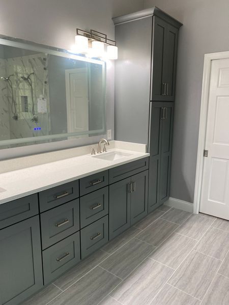 Gray and white bathroom with cabinetry, sink, and large mirror.