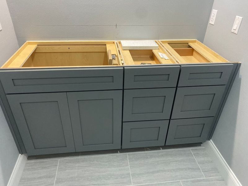 Gray bathroom vanity cabinet with drawers and doors, ready for installation.