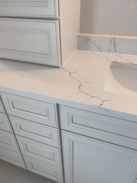 White bathroom vanity with marble countertop; cabinets, drawers, and sink are visible.