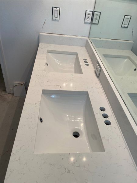 White double vanity with two sinks installed in a bathroom, with a mirror overhead.