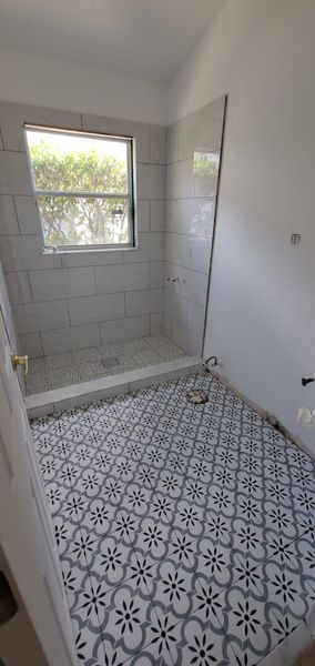 Newly tiled bathroom with patterned floor and shower area.