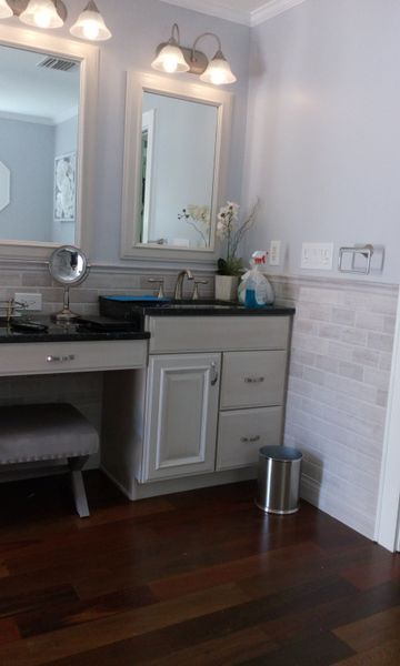 Bathroom with vanity, mirror, dark countertop, light blue walls, and dark wood floor.