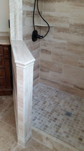 Bathroom shower with stone tile walls and mosaic tile floor.