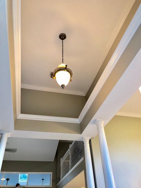 Ornate ceiling light hangs in a recessed ceiling with white trim and beige walls.