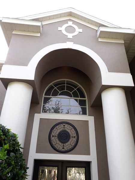 Beige and white building exterior with arched window, columns, and decorative accents.