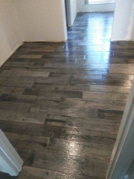 Gray wooden flooring, glossy finish. Hallway with white walls.