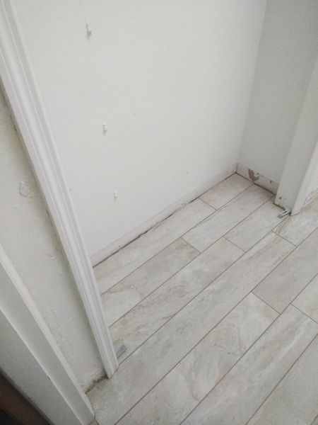Small closet with light wood-look tile flooring and white walls.
