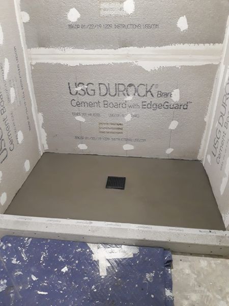 Shower stall with gray cement base and Durock cement board walls.