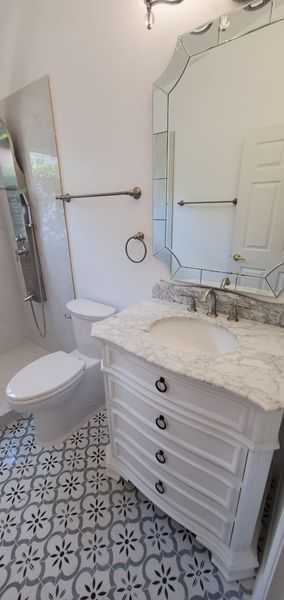 Bathroom with white vanity, patterned floor, and large mirror.