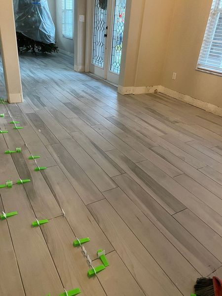 Interior with newly installed wood-look floor tiles. Green leveling clips are in use.