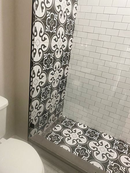 Bathroom with patterned tile wall and floor, white brick wall, and toilet.