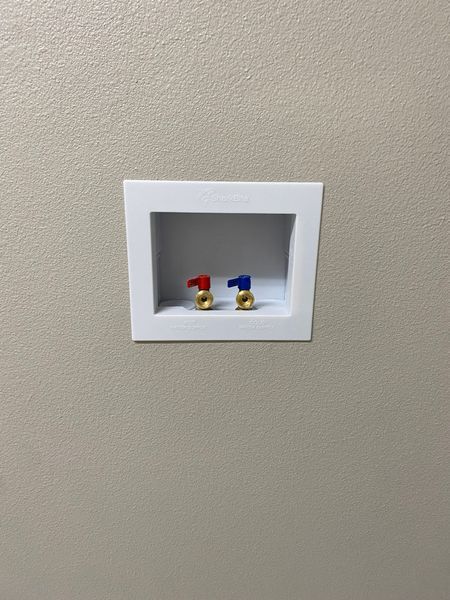 White recessed box on wall with red and blue water shutoff valves.