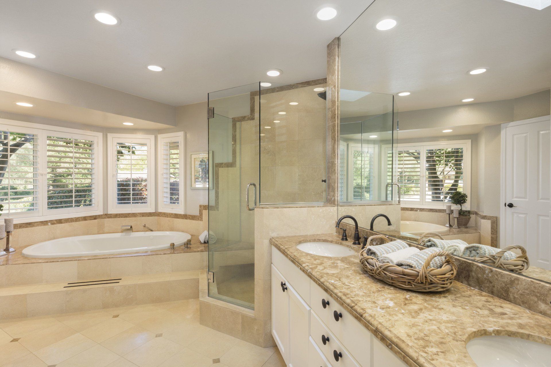 Spacious bathroom with a walk-in shower, soaking tub, double vanity, and large mirrors. Beige and white tones.