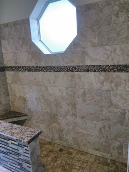 Tiled shower with octagon window; beige tiles, mosaic trim, built-in bench.