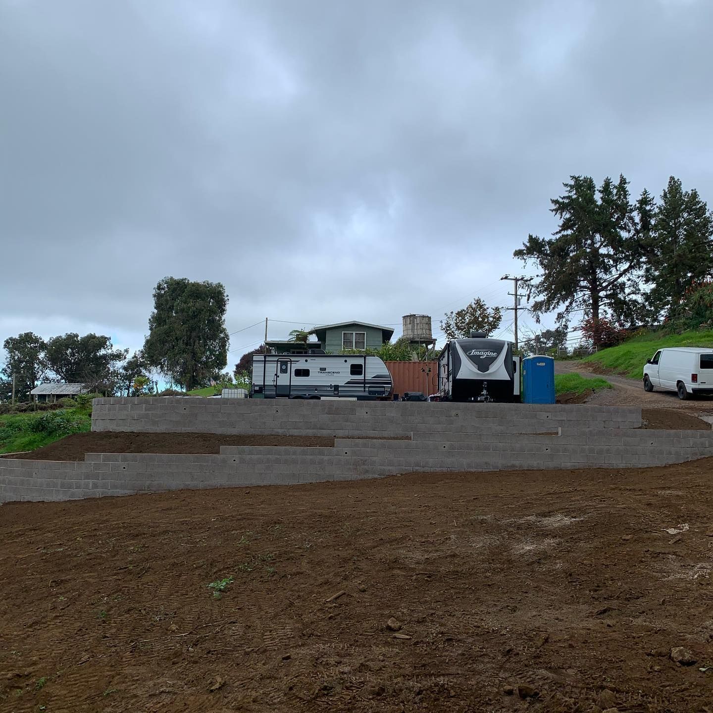A rv is parked in a dirt lot next to a house