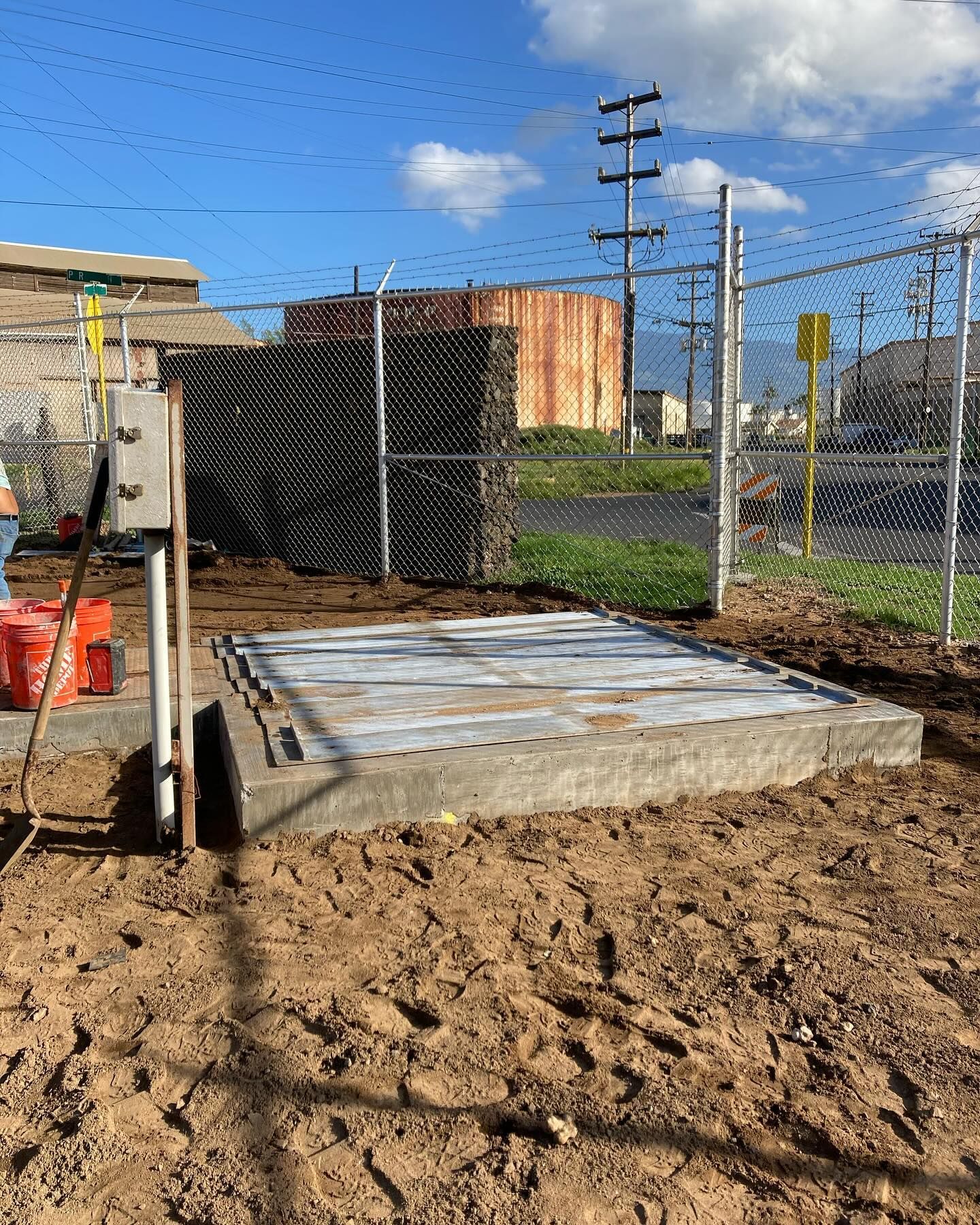 A concrete platform is sitting in the middle of a dirt field next to a chain link fence.