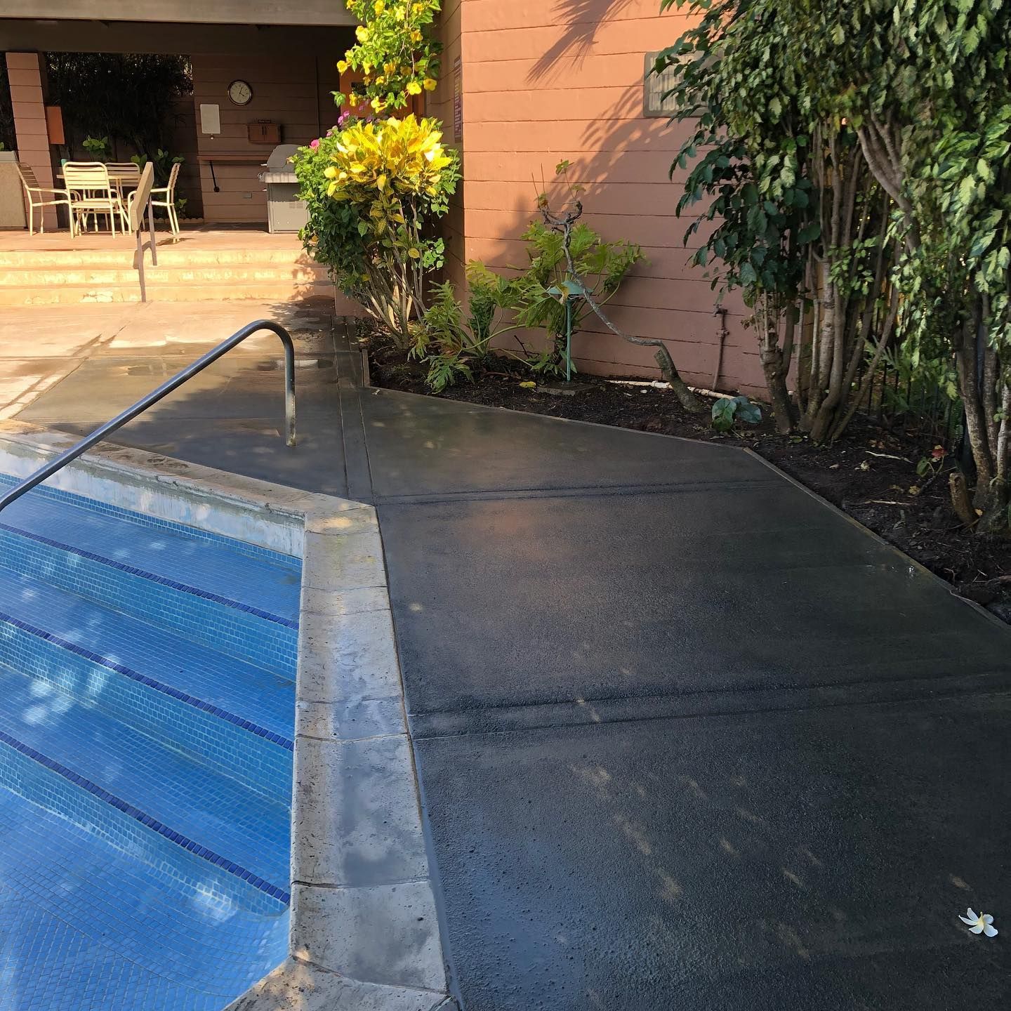 A swimming pool with a concrete walkway leading to it