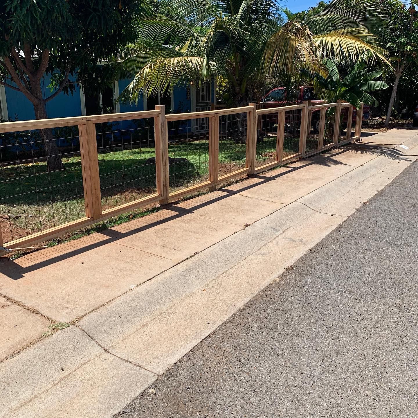 A wooden fence along a sidewalk in front of a house