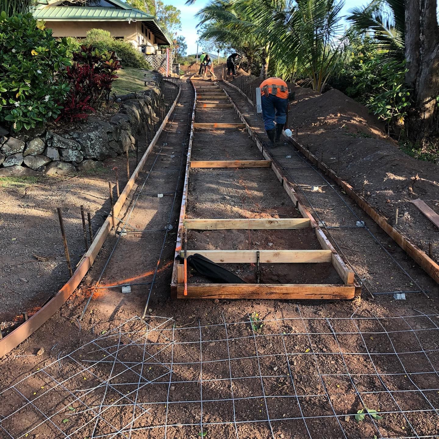 A group of people are working on a concrete walkway.