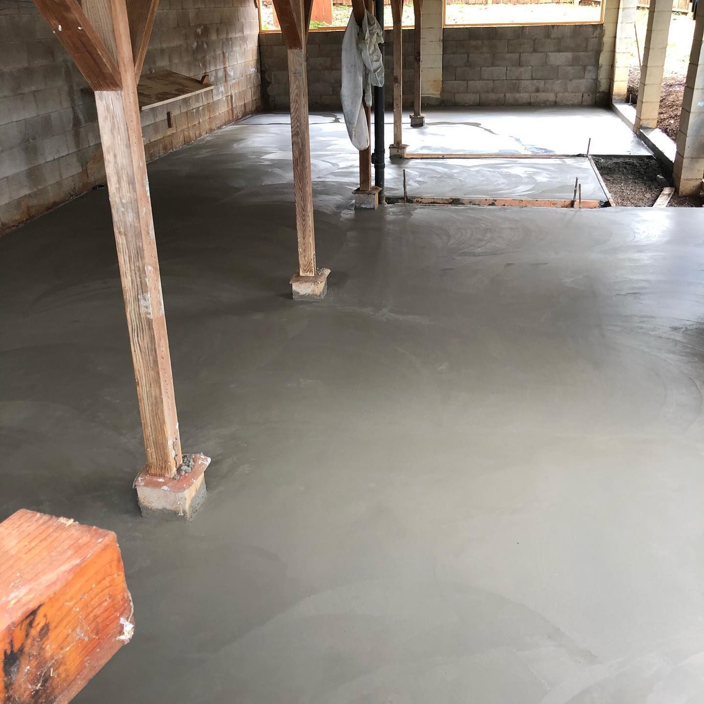 A concrete floor in a basement with wooden beams.