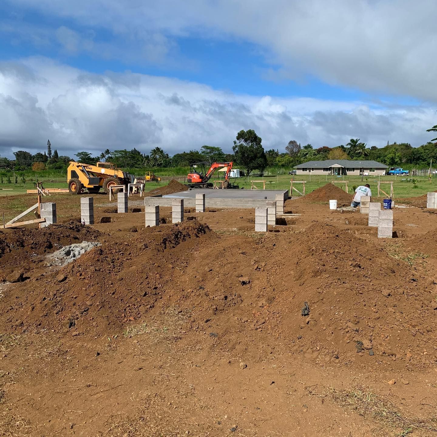 A construction site with a lot of dirt and a house in the background