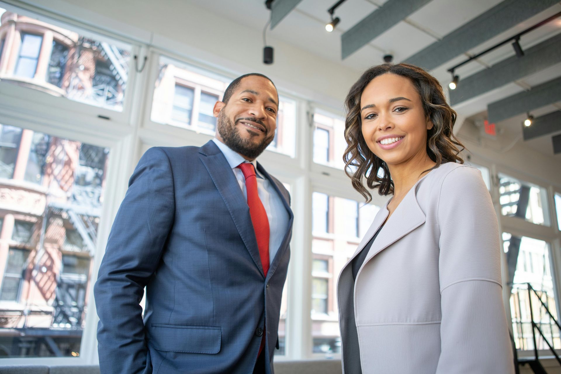 a man and a woman are standing next to each other in front of a window .