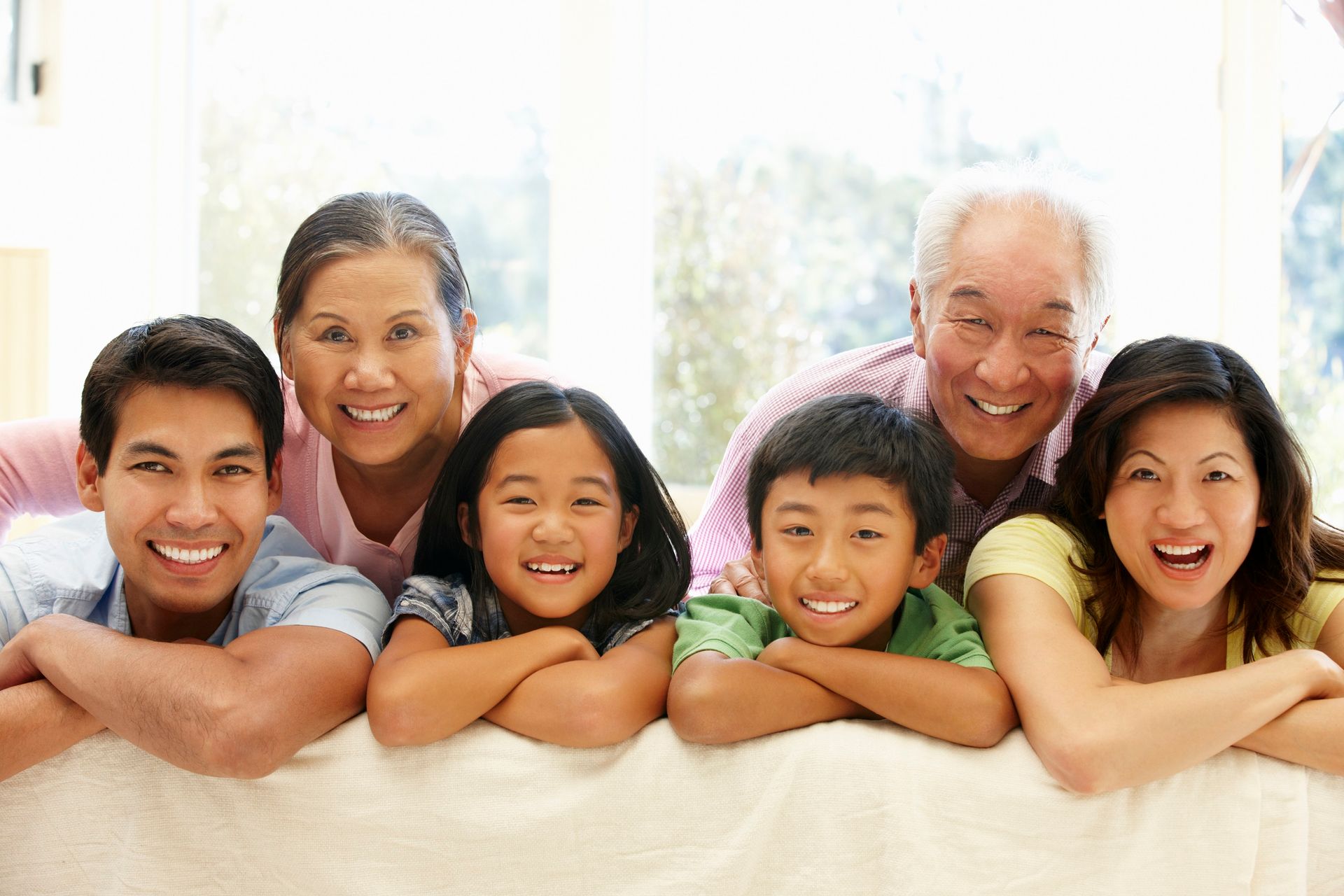A family is laying on a couch with their arms crossed and smiling.